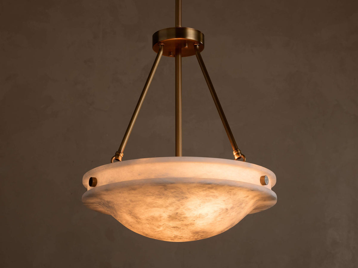 Front view of the Edith Pendant with a brass finish and a glowing, marbled alabaster stone shade.