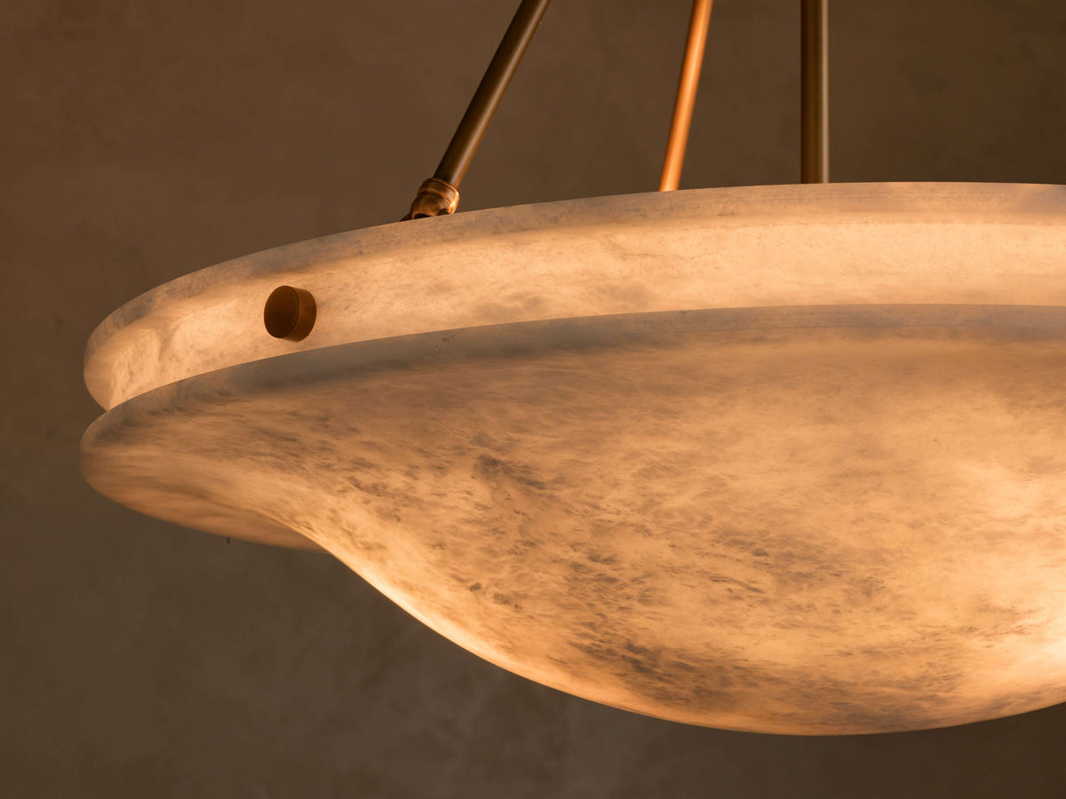 Close-up of the glowing alabaster shade of the Edith Pendant, revealing its translucent white marbled texture and brass accents.