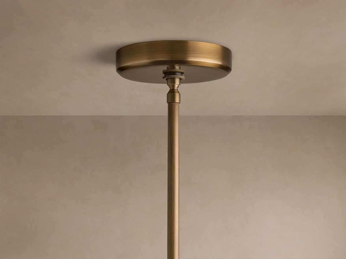 Close-up of the brass finish ceiling canopy and suspension rod of the Edith Pendant attached to a beige ceiling.