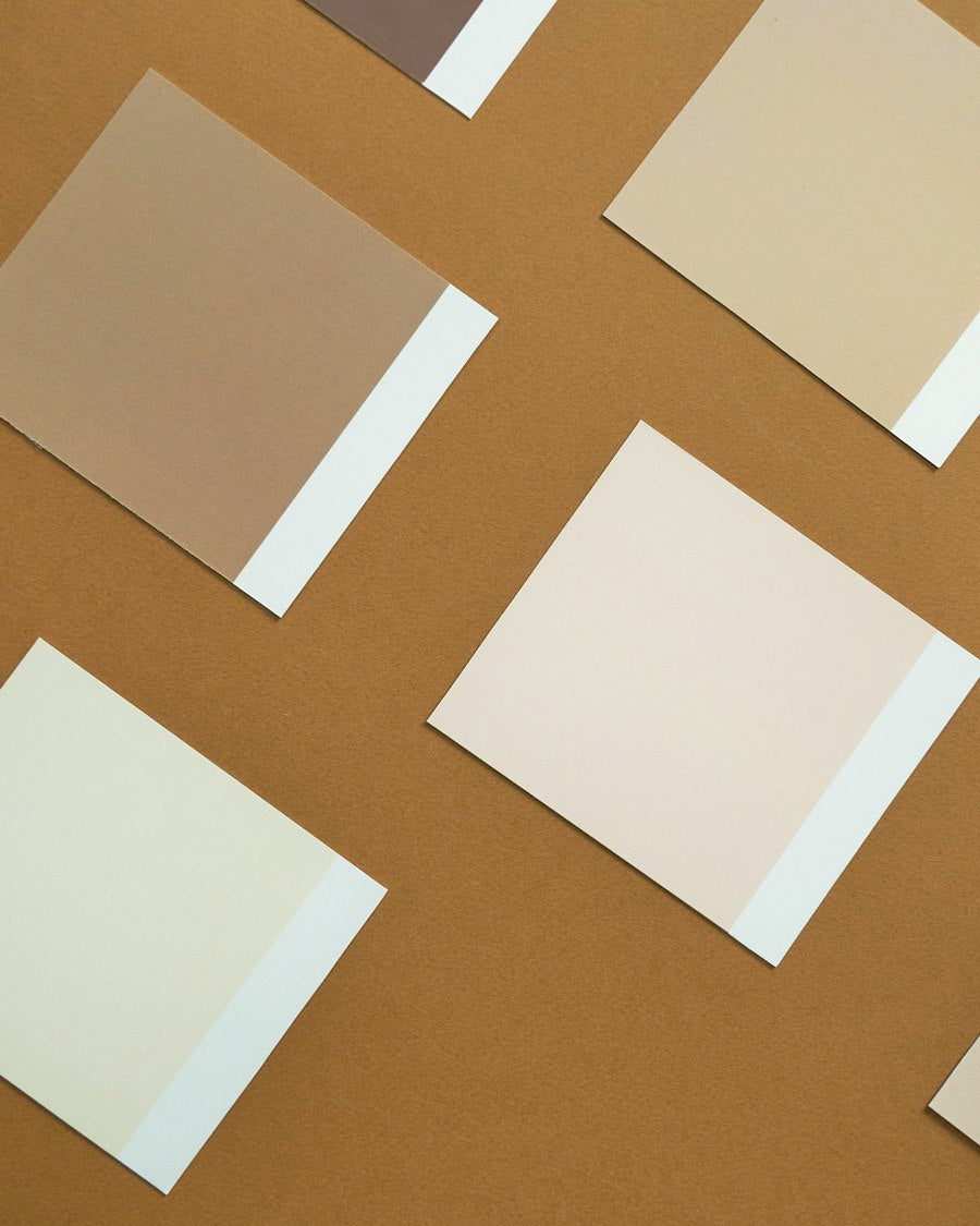 Neutral finish sample cards laid out on a warm ochre ground