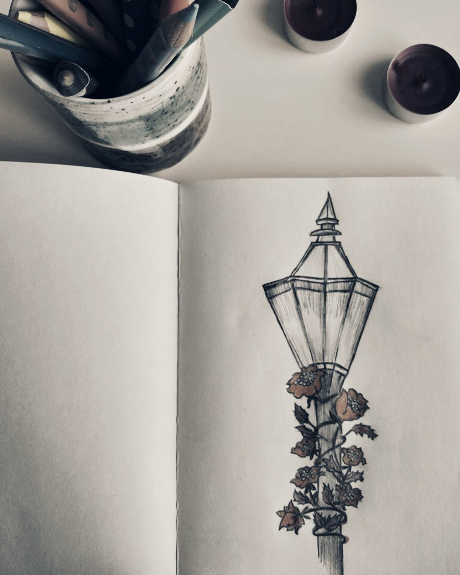 Hand-drawn pencil sketch of an ornate lantern in an open sketchbook