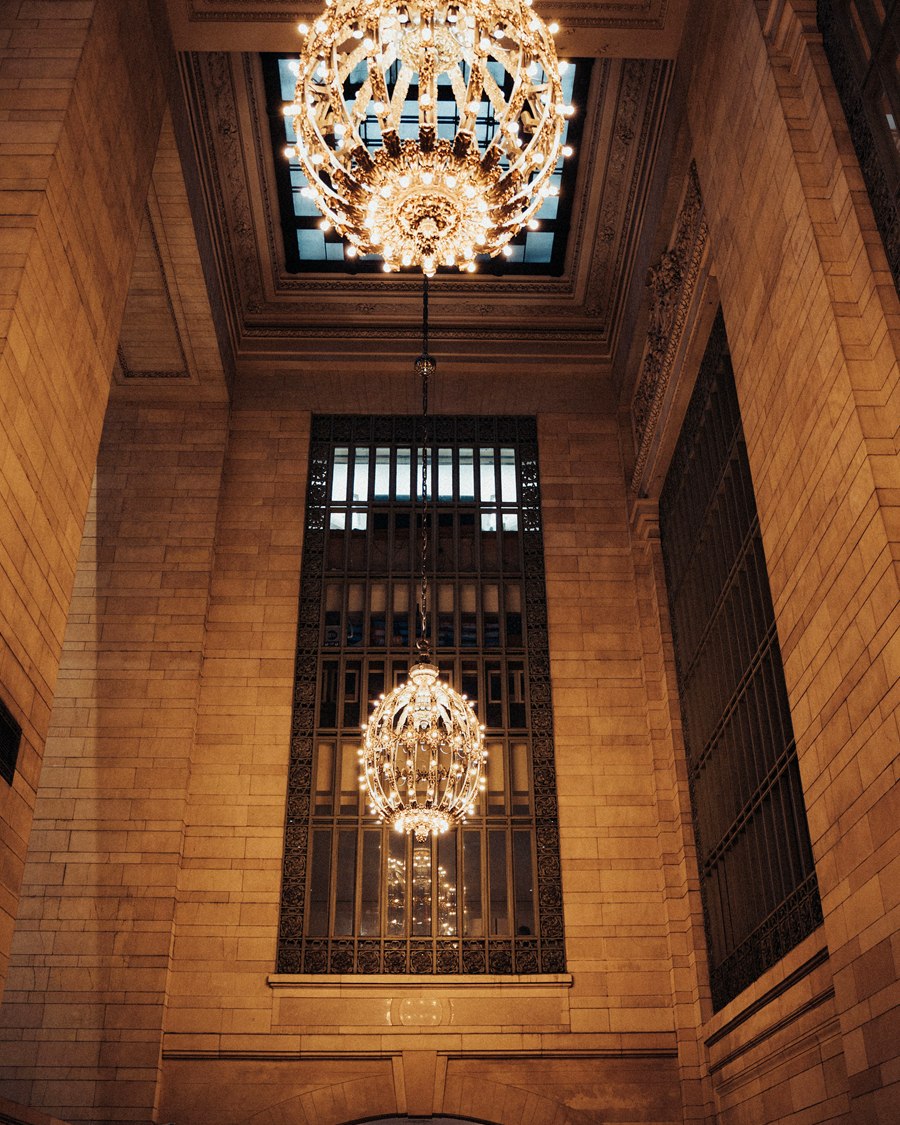 Two large chandeliers hanging in a tall timber-lined double-height void