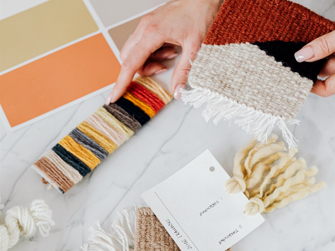 Hands arranging fabric and material samples on a stone surface