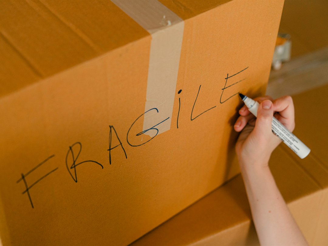 Hand marking FRAGILE on a sealed kraft shipping carton