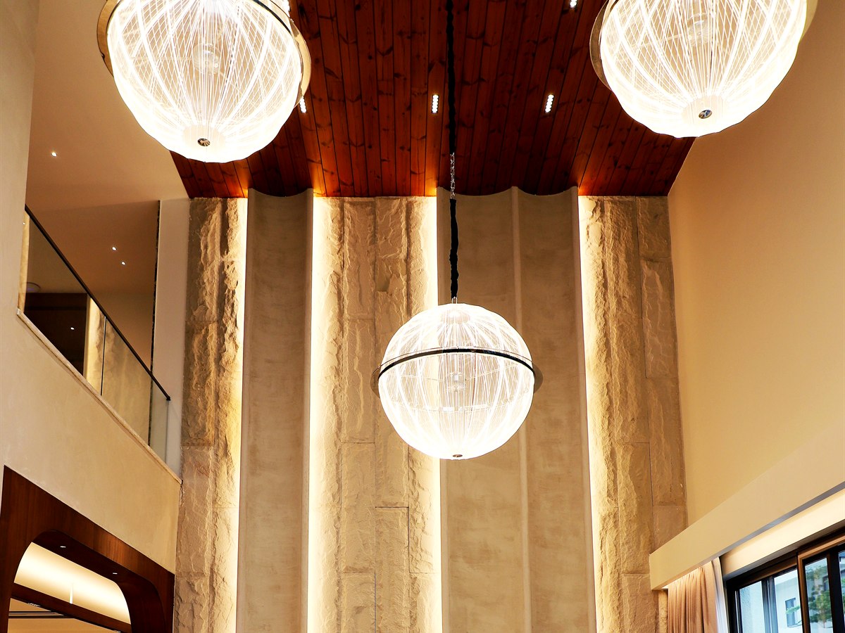 Ribbed glass pendants at staggered drops in a double-height travertine space