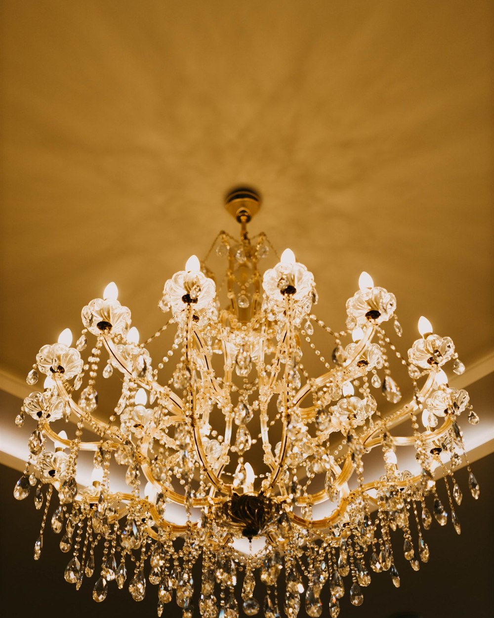 Gold crystal chandelier lit against a warm domed ceiling
